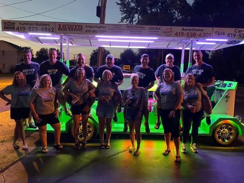 Group of friends posed at night next to the green-lit trolley
